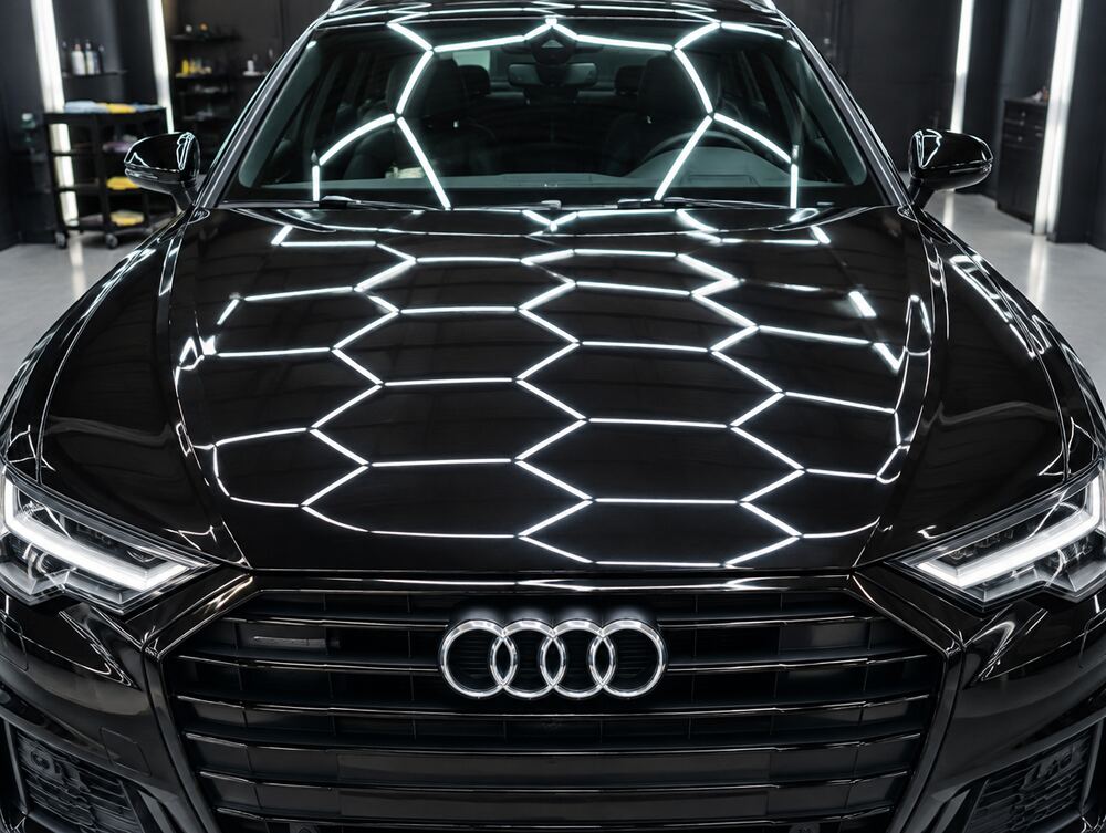 Glanzende motorkap van een zwarte Audi A6 na polijsten en coaten