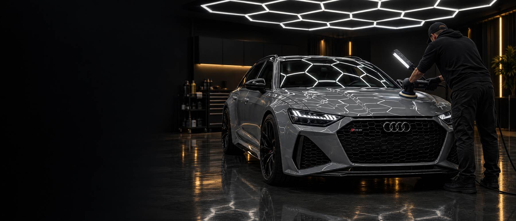 Polierder werkt aan een Audi RS6 onder het honingraatlicht