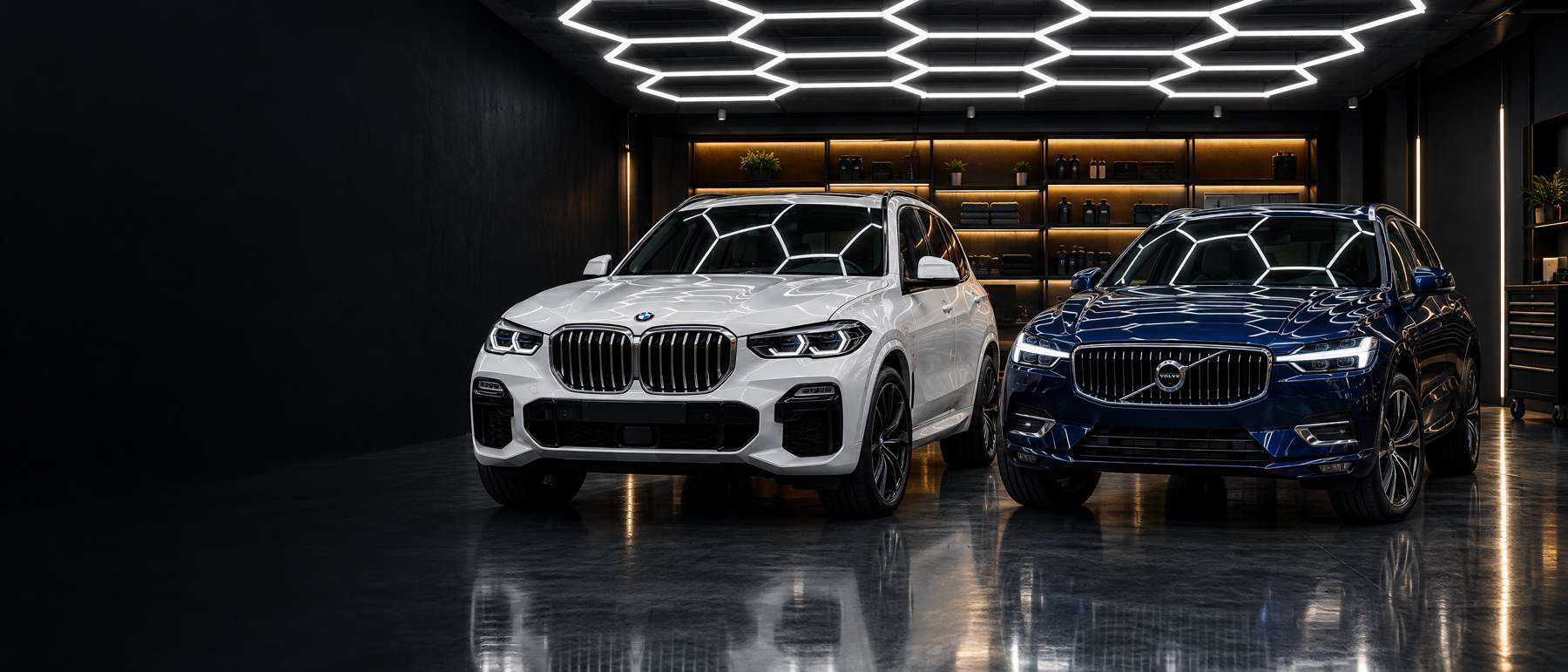 Witte BMW X5 en blauwe Volvo XC60 onder het honingraatplafond van de studio